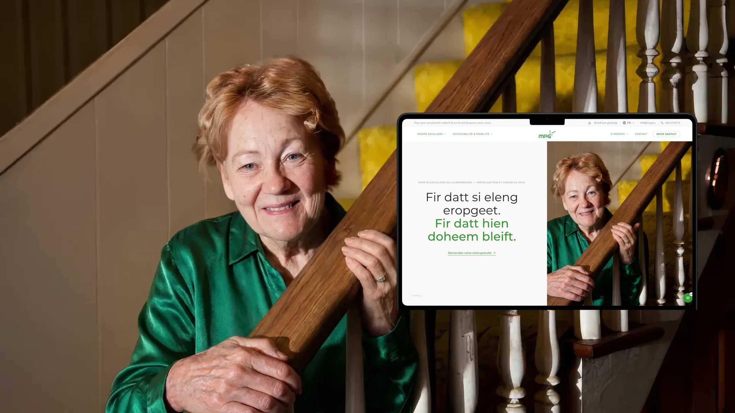 Une femme âgée souriante dans son escalier, à côté d’un mockup du site MPG portant « Fir datt hien doheem bleift ».